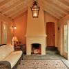 Inside, sunroom has a vaulted ceiling with exposed beams and a real masonry wood burning Rumford fireplace.   Bluestone terrace and exterior stucco continue indoors.  Plank door next to fireplace leads to garage.  For homeowners, this is like having a vacation house in their backyard.