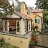 Sunroom has French doors on three sides that open to a raised terrace. Retaining wall with stone cap is at bench height.  Stepped terraces provide an easy transition from alley garage to house.
